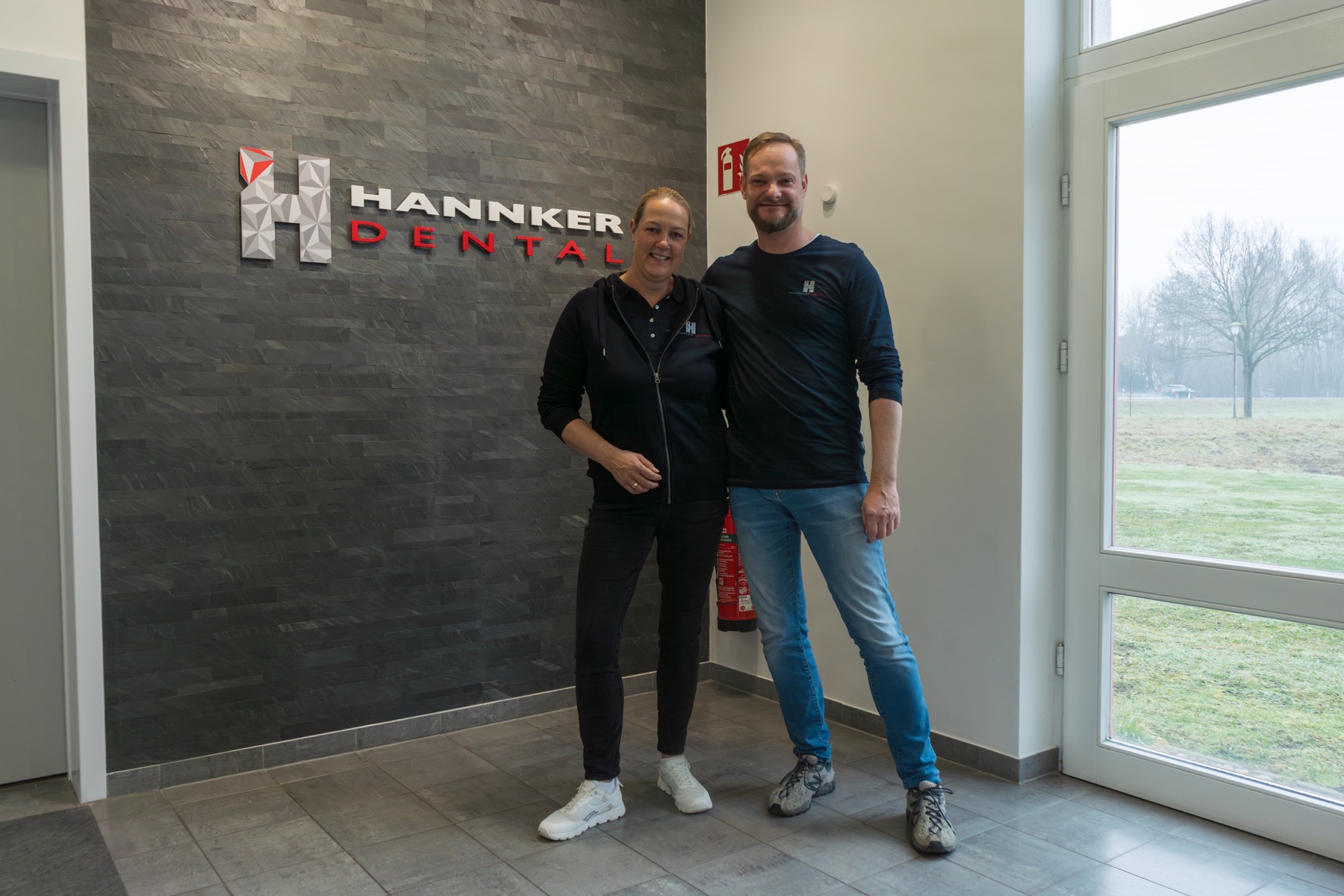 Team von Hannker Dental vor dem Firmenlogo